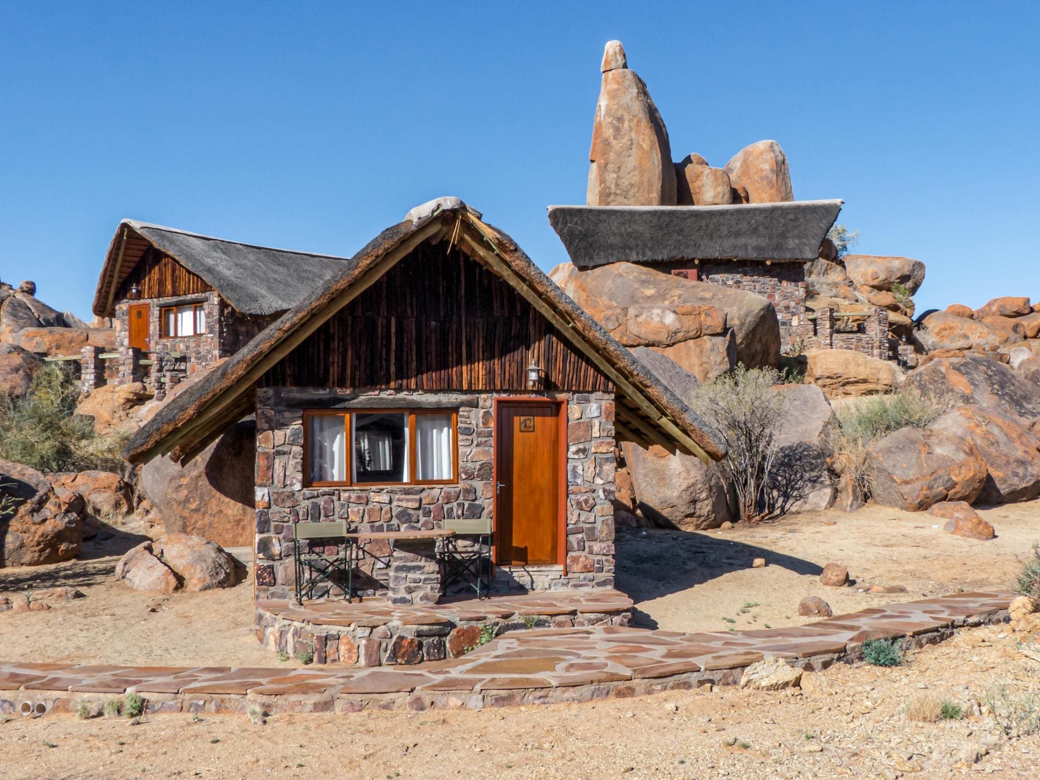 Cozy stone cabin nestled among natural rock formations in Namibia's desert setting.